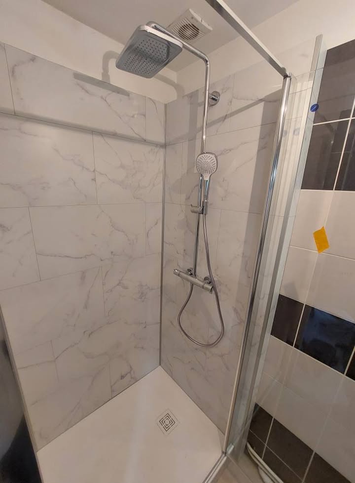 Photo réelle — Espace douche : habillage mural clair et paroi vitrée à Localisation non précisée